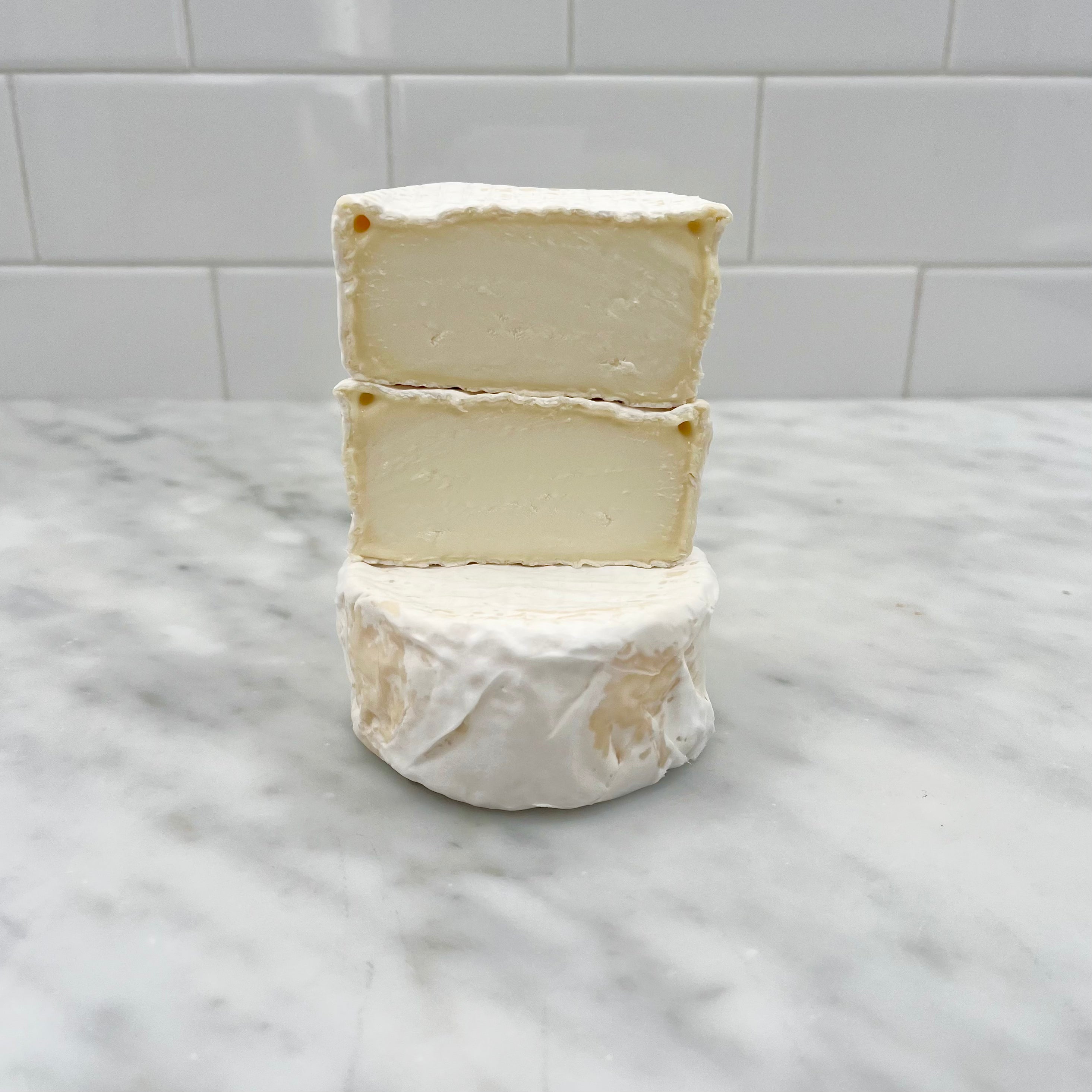 Three stacked pieces of white cheese on a marble surface.