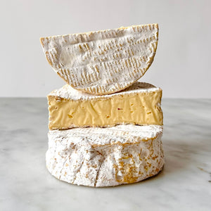 Three stacked cheeses on a white surface.