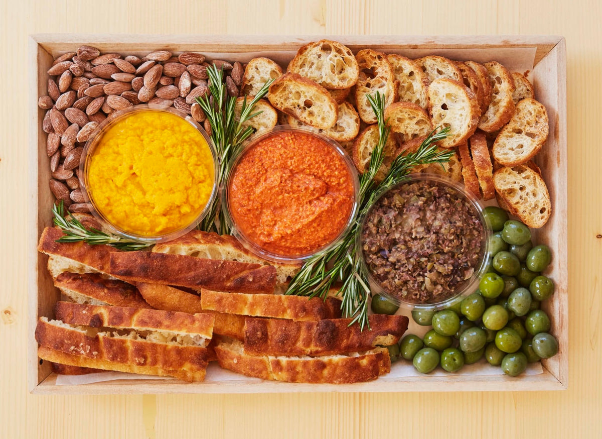 Appetizer platter with dips, toasted bread, and nuts.
