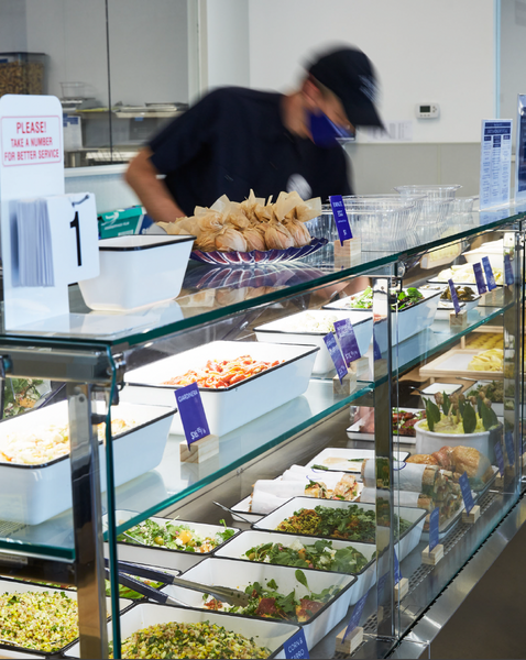 An employee serving prepared foods from our in-store case.