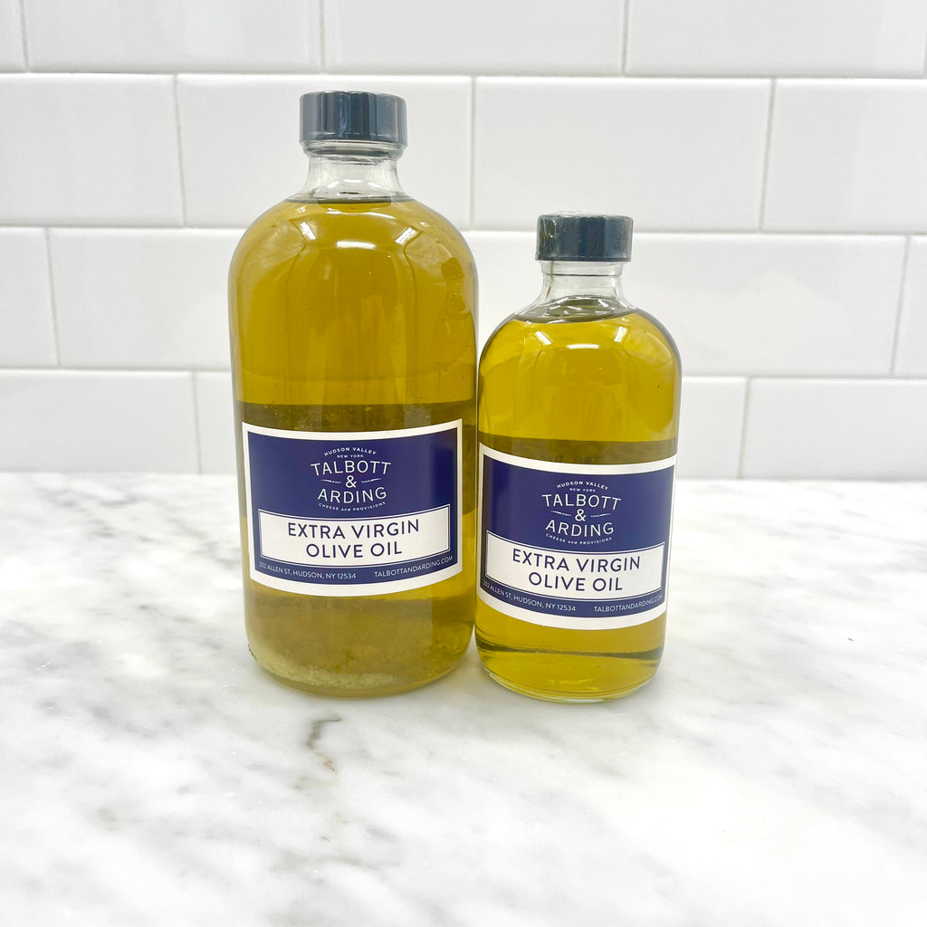 Two bottles of extra virgin olive oil on a marble countertop.