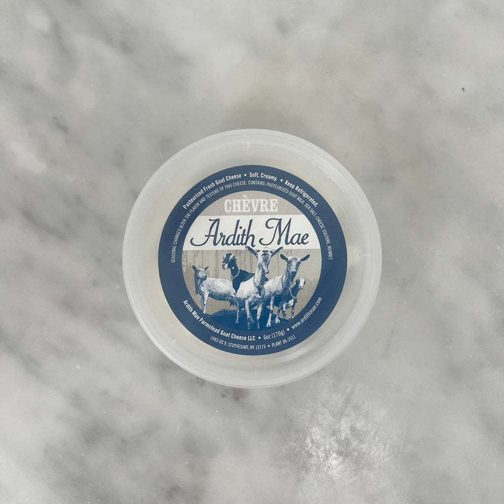 Container of goat cheese on a marble surface.