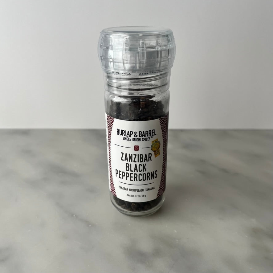 Bottle of Zanzibar black peppercorns on a counter.