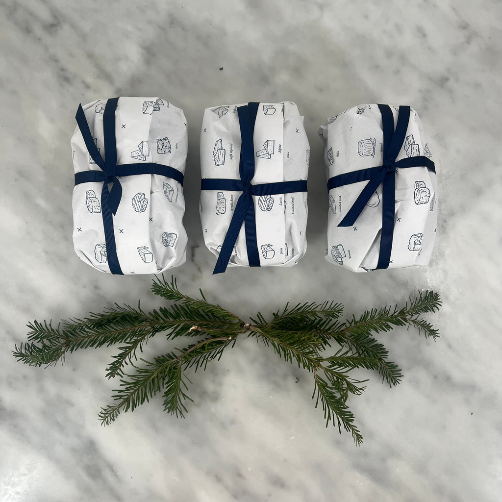 Three wrapped gifts above a sprig of evergreen.