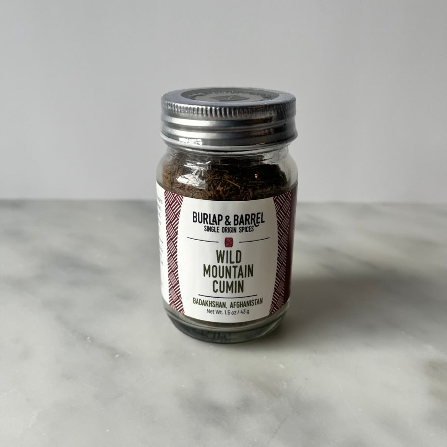 A jar of wild mountain cumin on a marble surface.