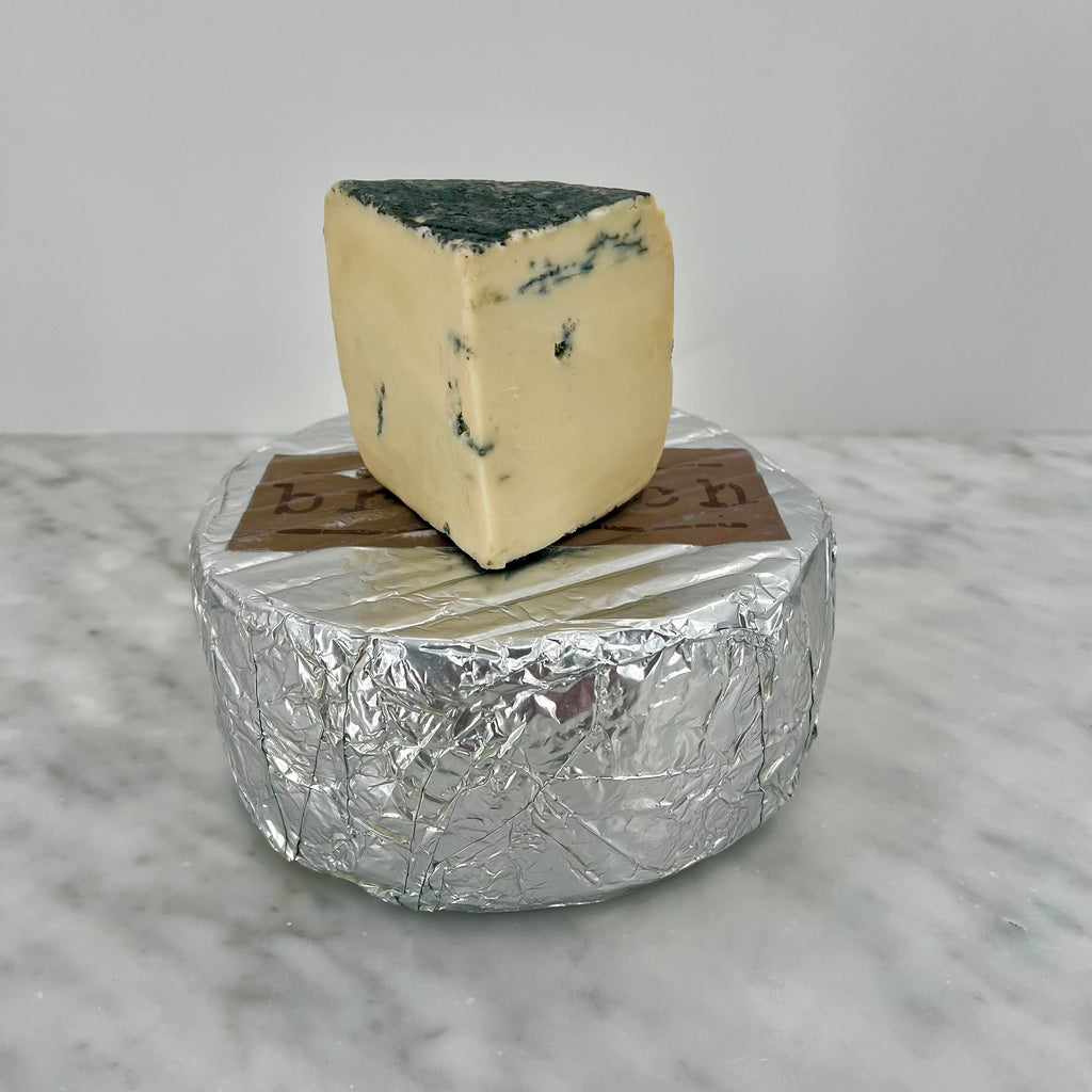 A wedge of blue cheese on foil.