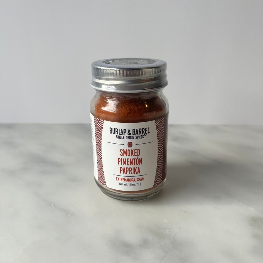 Glass jar of smoked paprika on a countertop.