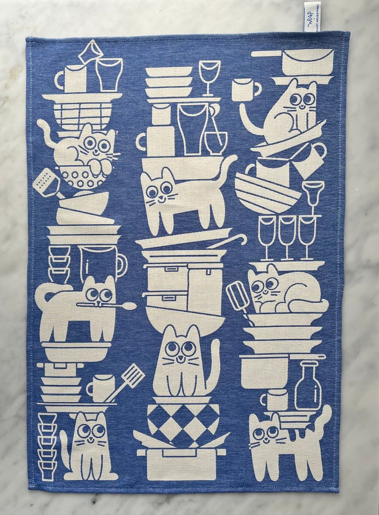 A stylized blue and white towel featuring illustrations of cats with kitchenware and coffee-making items.