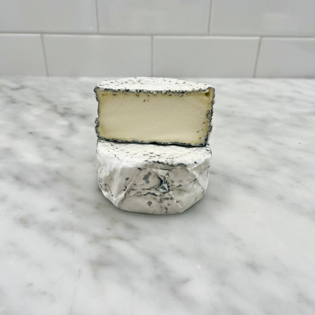 A wheel of cheese on a marble surface.