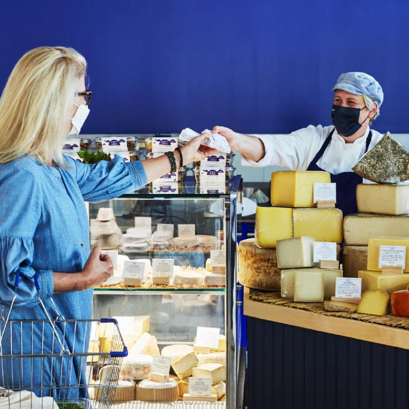 A customer being passed cheese from the cheese counter.