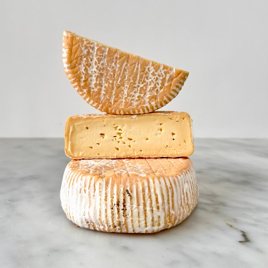 Three stacked cheeses on a marble surface.