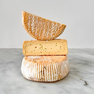 Three stacked cheeses on a marble surface.