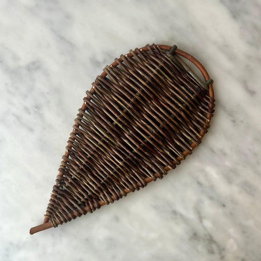Woven rattan fan on marble surface.