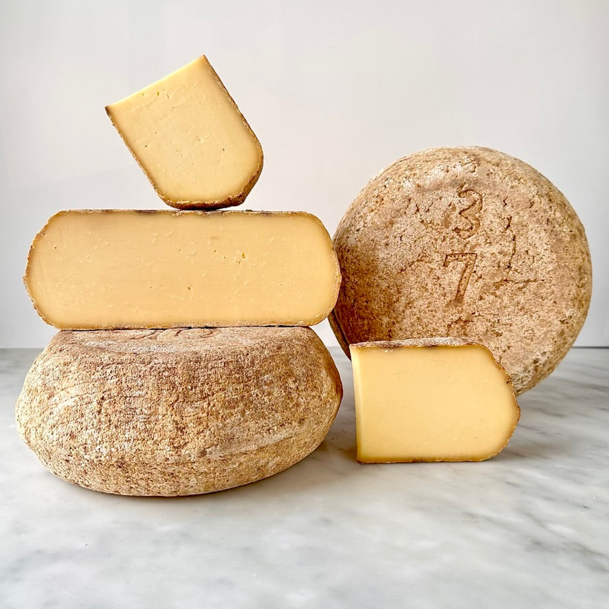 Wheel and wedges of cheese on a table.