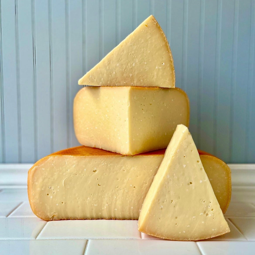 Three wheels of cheese on a table.